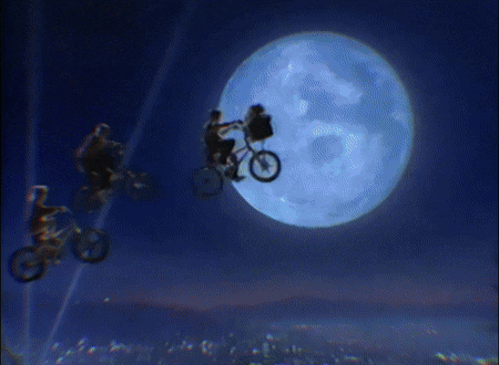 a person riding a bike in front of a large full moon