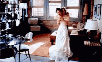 a woman in a white wedding dress is being held by a man in a living room