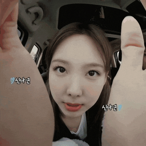 a close up of a woman giving a thumbs up in a car with korean writing on her face