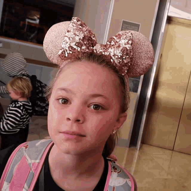 a girl wearing minnie mouse ears and a backpack