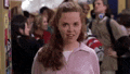 a woman in a pink sweatshirt is standing in a crowd of people in a store .
