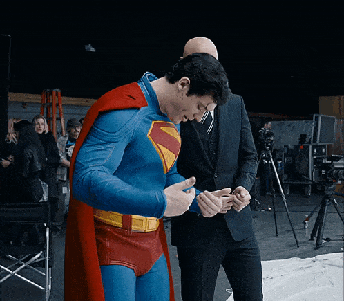 a man in a superman costume is talking to another man in a suit