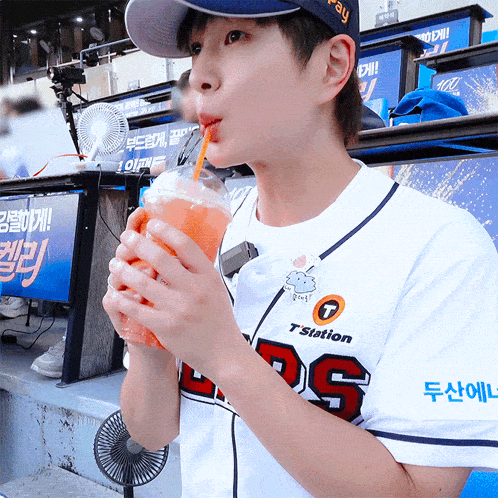 a young boy wearing a 7 station jersey drinks from a plastic cup