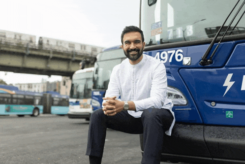 a man sits on the front of a bus with the number 4976 on the side