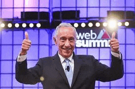 a man in a suit and tie is giving two thumbs up in front of a web summit sign .