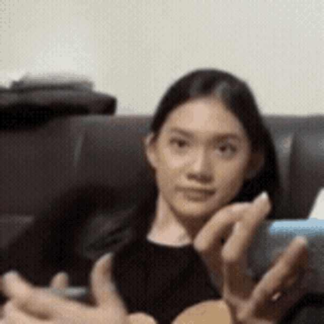 a woman is sitting on a couch holding a cell phone in her hand .