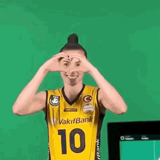 a woman in a yellow volleyball jersey is giving a thumbs up sign .