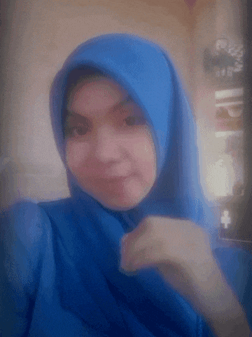a woman wearing a blue hijab is taking a picture of herself