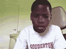 a young boy wearing a white shirt that says souderton on it