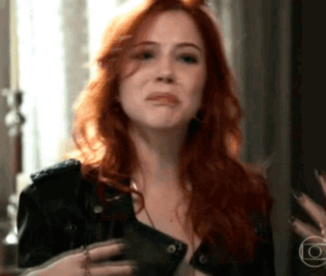 a woman with red hair is wearing a leather jacket and a necklace