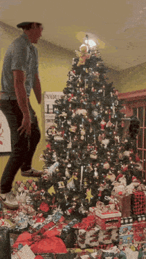 a man jumps in front of a christmas tree surrounded by gifts