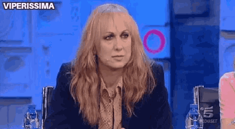 a woman with blonde hair is sitting in front of a microphone with the words viperissima above her .