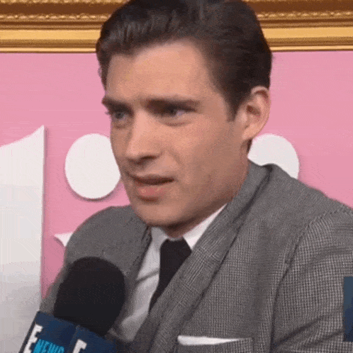 a man in a suit is talking into a microphone .