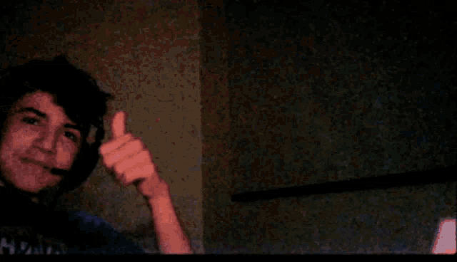 a man wearing a headset waves his hand in the dark