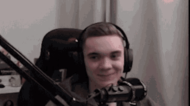 a young man wearing headphones and a microphone is sitting in front of a microphone .