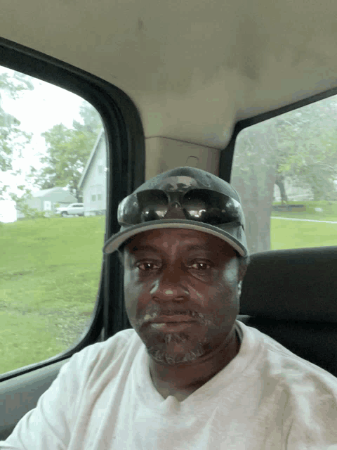 a man wearing a hat and sunglasses sits in a car