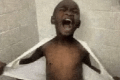 a shirtless child is taking a shower with a towel over his shoulders .
