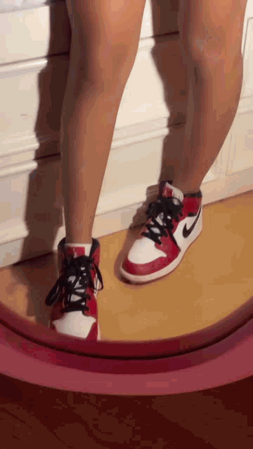 a person is standing in front of a mirror wearing red and white nike shoes