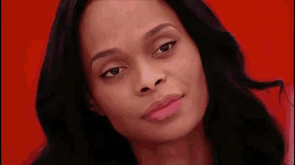 a woman with long black hair is looking at the camera with a red background .