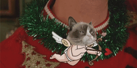 a grumpy cat is holding a cupid 's bow and arrow on a red sweater .
