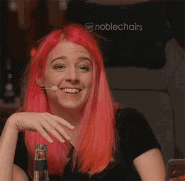 a woman with pink hair is smiling in front of a noble chair