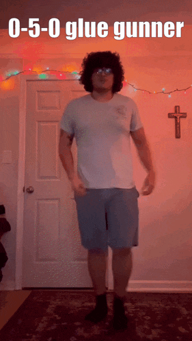 a man with curly hair is standing in front of a door with the words 0-5 0 glue gunner on it