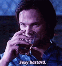 a man is drinking a glass of whiskey and saying `` sexy bastard '' .