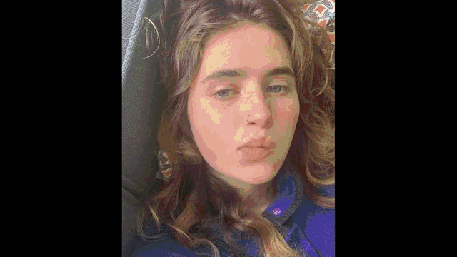 a close up of a woman 's face with a nose ring and a blue shirt .