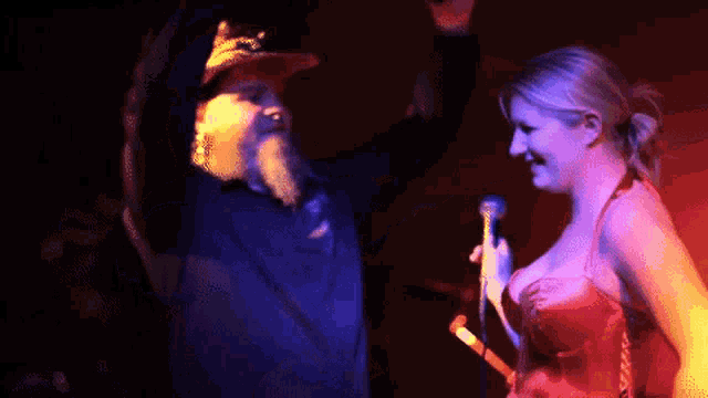 a man with a beard stands next to a woman in a red dress
