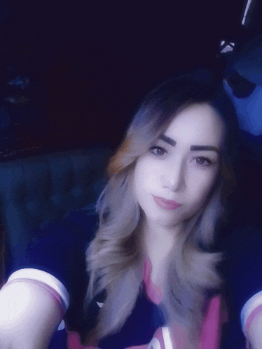 a woman taking a selfie in a dark room with a purple background