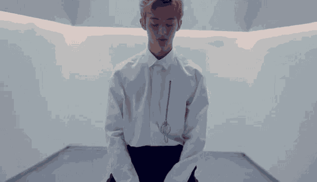a man in a white shirt and black pants is kneeling down in a room .