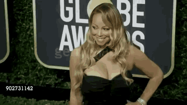 a woman in a black dress is standing on a red carpet at a globe awards event .