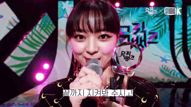 a woman is holding a trophy in front of a studio k logo