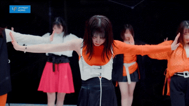 a group of girls are dancing in front of a blue sign that says upfront works