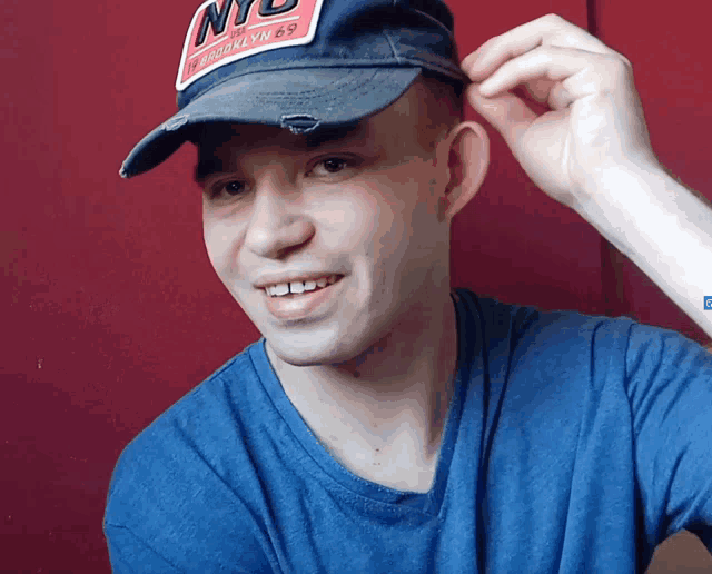 a man wearing a blue shirt and a nyc baseball cap