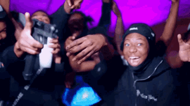 a group of people are posing for a picture and one of them is wearing a black hoodie with the word supreme on it
