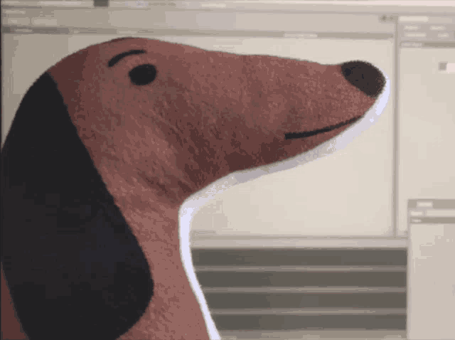 a stuffed dachshund is sitting in front of a monitor