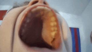 a close up of a person 's mouth with a glass in it .