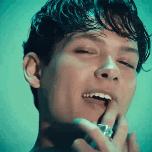 a close up of a man 's face with his eyes closed and his finger on his lips .