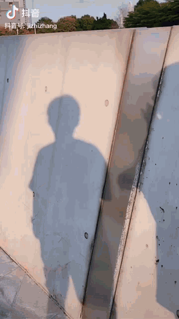 a shadow of a person is cast on a concrete wall with a watermark that says jizhizhang