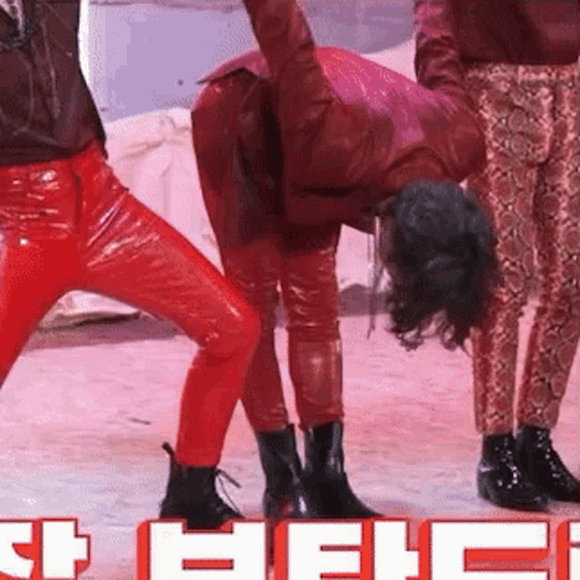 a group of people wearing red pants and black boots are dancing in front of a sign that says ' hell '