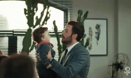 a man in a suit is holding a baby in his arms and kissing it .