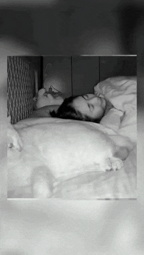 a black and white photo of a man and a woman sleeping on a bed