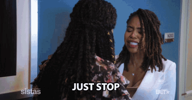 two women are standing next to each other and the word just stop is visible