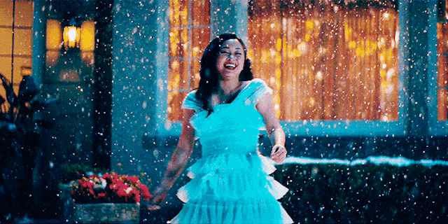 a woman in a blue dress is standing in front of a house in the snow .