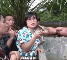 a group of people are standing around a woman who is holding a cigarette in her hand .