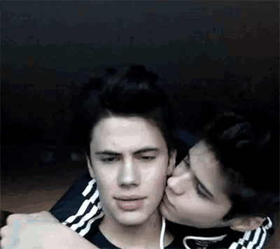 two young men are hugging and kissing each other .