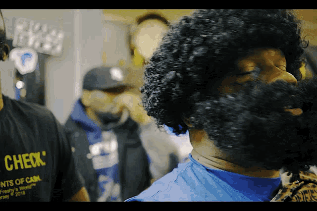 a man with a beard wears a blue shirt that says check