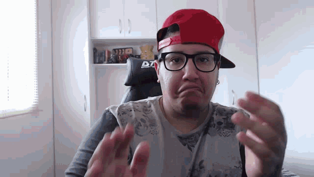 a man wearing a red hat and glasses is making a face