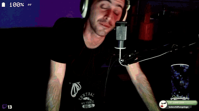 a man wearing headphones is talking into a microphone with the number 13 on the screen